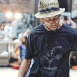 Dançarino de breakdance se apresenta em um ambiente de hip hop, diante do público.