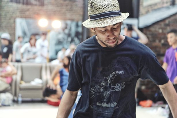Dançarino de breakdance se apresenta em um ambiente de hip hop, diante do público.