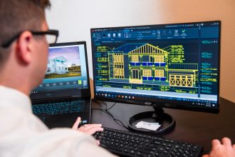 Arquiteto analisa projetos detalhados de uma residência exibidos em dois monitores, em um escritório moderno.